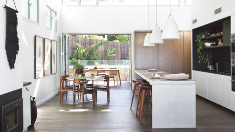 Calm and classic dinning and kitchen interior with fireplace, white walls, framed pictures on wall and wooden chairs