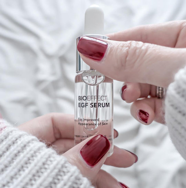 Woman holding BIOEFFECT EGF Advanced Anti-Aging Serum over a white background