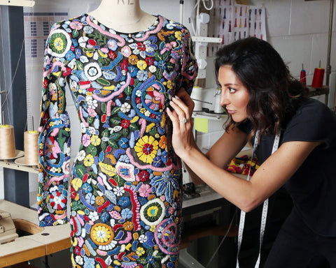 nadine merabi looking closely at dress on a mannequin