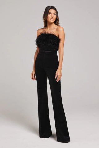 Woman wearing strapless black jumpsuit with belt and feather trim