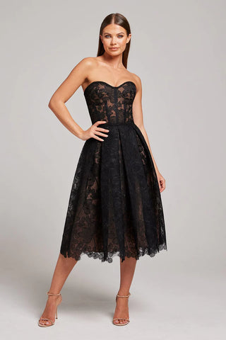 Woman wearing strapless black dress with embroidered flower detailing 