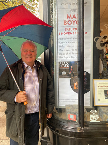 Max Boyce standing under a big multicoloured umbrella outside the Cardiff Waterstones bookshop.