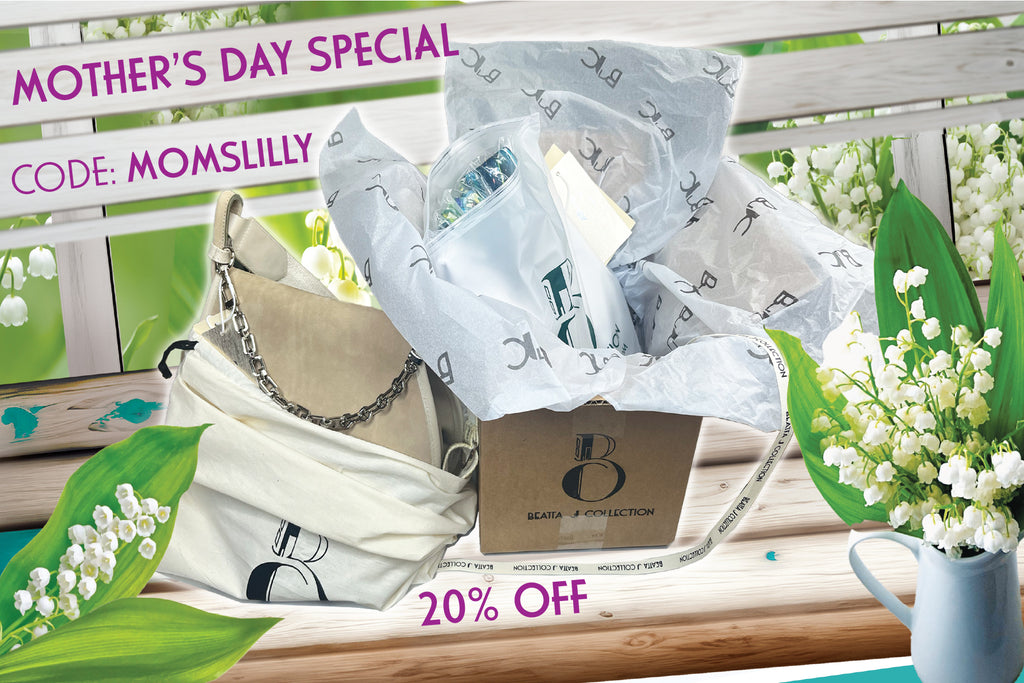 white, wooden bench with the Beatta J Collection fashion brand gift box for Mother's Day Special discount. The bench is surrounded with white lilly of the valley flowers.