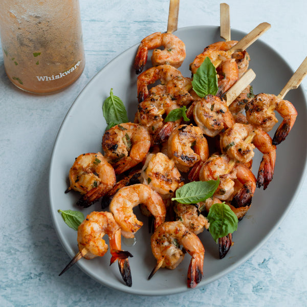 grilled shrimp sitting on a plate next to a Whiskware Dressing Shaker