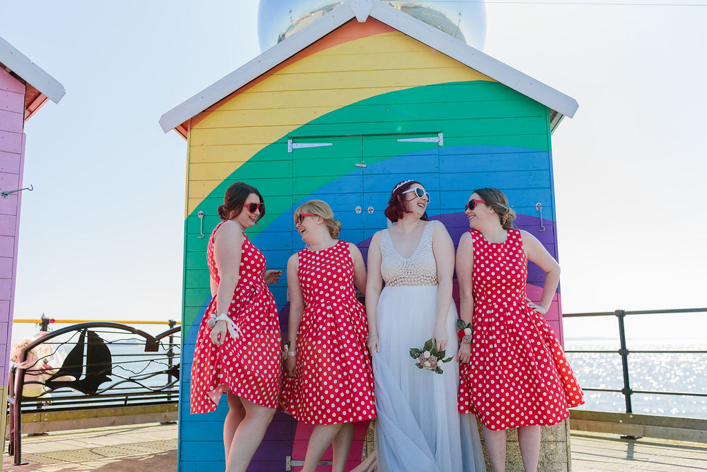 Bride and Bridesmaid in front of a rainbow beach hut