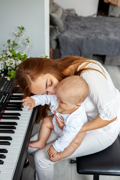 Mother and baby sitting in front of the piano
