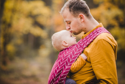 Father kissing baby's head while babywearing