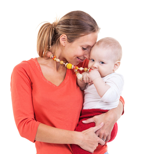 Mother holding her baby while they chew on her necklace