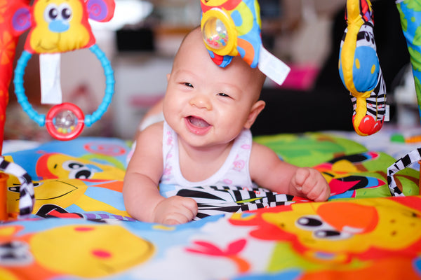 Smiling baby having tummy time with brightly coloured toys