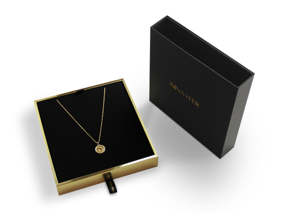 Nina veer black outside, gold inside rigid sleeve box with black ribbon and hot foil stamped logo