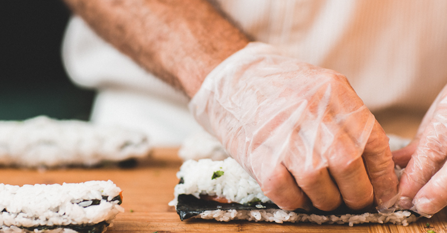 Sushi being rolled by a disposable glove