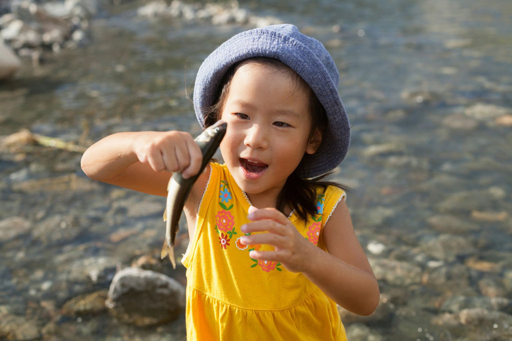 Small girl holding a fish by the river