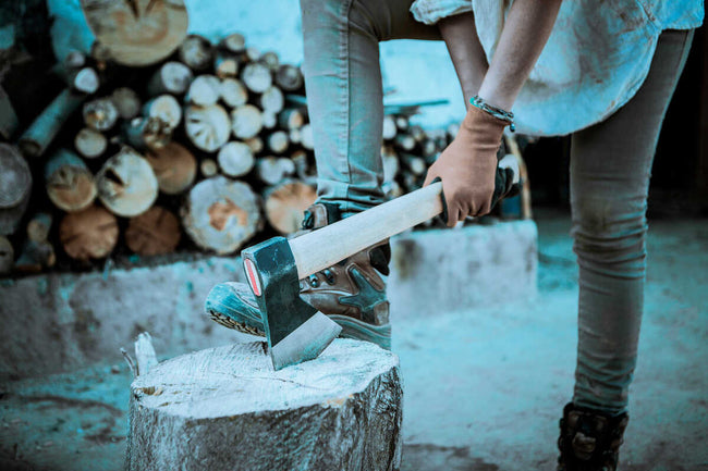 a woman in work boots is chopping wood