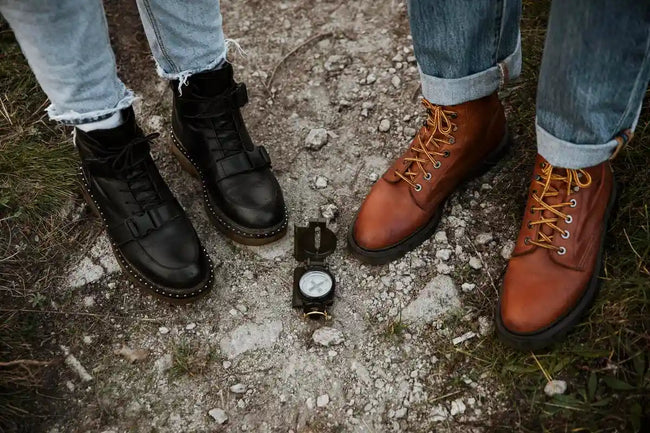 couple road trip in faux and real leather boots standing at the rock next to with compass
