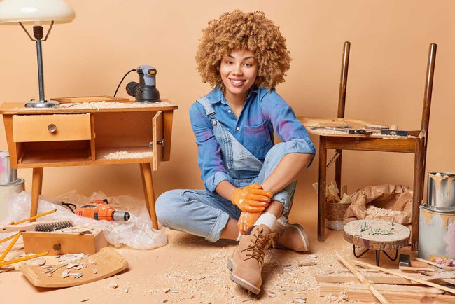 smiling female carpenter sitting on the floor, taking break after work