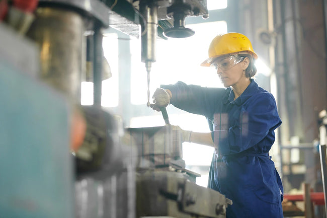 Female mechanic in work gear and work boots repairing machines