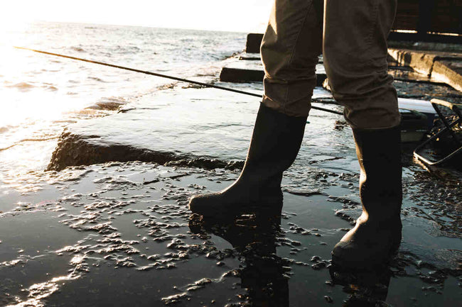 Close up of a fisherman in deck boots catching a fish