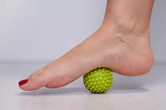 female foot step on massage ball to relieve Plantar fasciitis