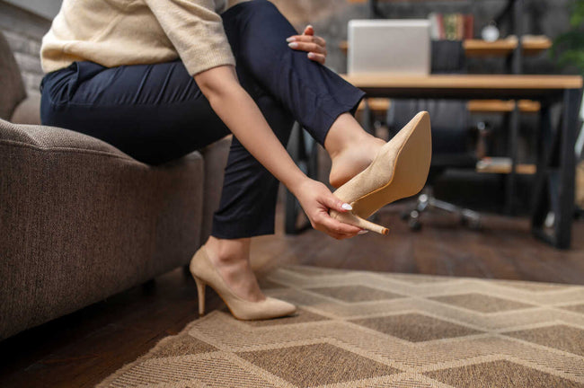 Female putting off stylish high-heeled shoes