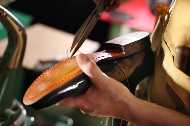 the master sews the leather sole on the shoe