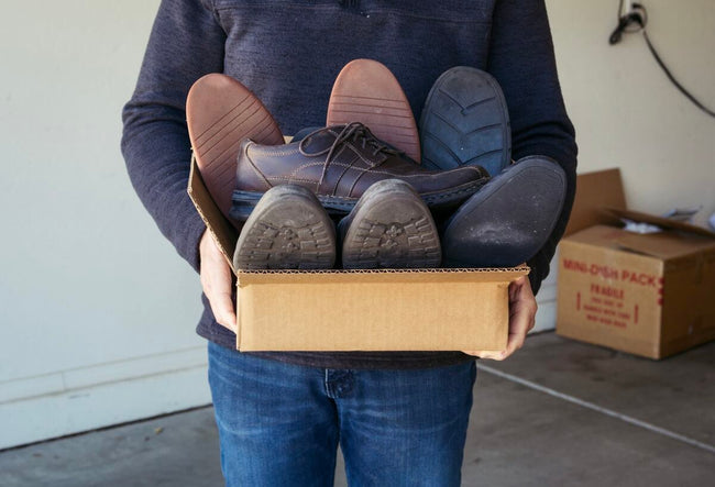 Adult male carrying a box of used shoes being donated