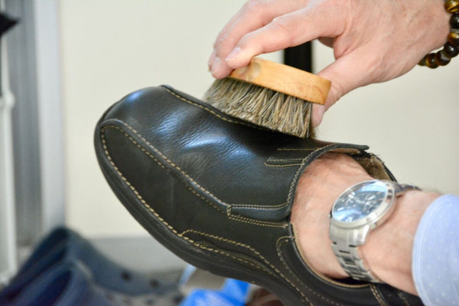  a man cleans his shoes with a brush