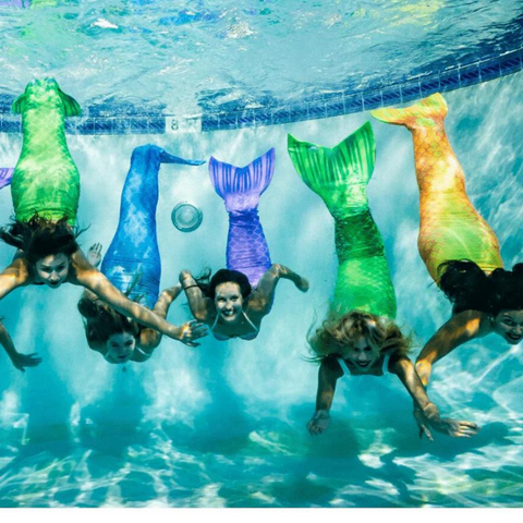 5 mermaids underwater smiling at the camera / mermaid lesson