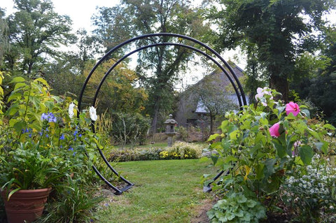 Solid Steel Moon Gate Surrounded by pink blooming flowers - Henderson Garden Supply