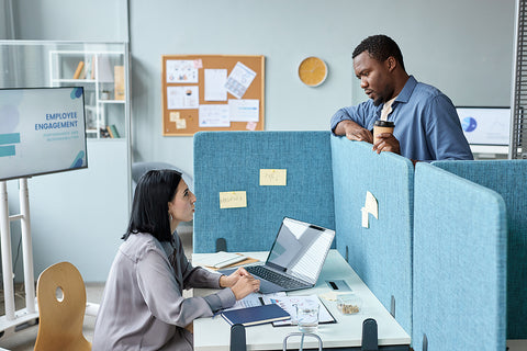Two people conversing over their shared cubicle wall