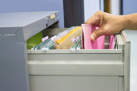 A person pulling a file out of a lateral filing cabinet