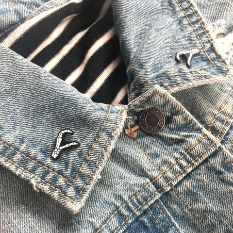 Skeleton hands forming a heart shape pins on the lapel of a denim vest for punk style. 