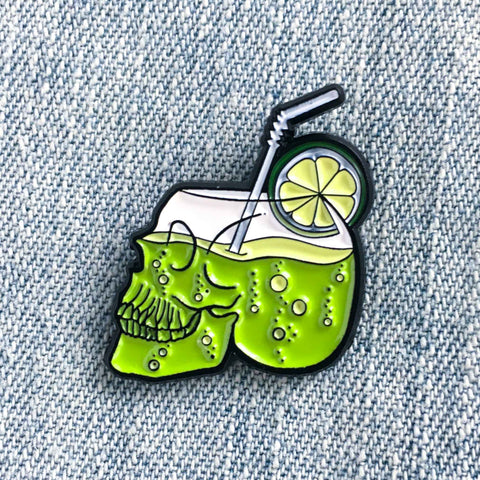 A cool lapel pin of a cocktail in a glass shaped like a skull. 