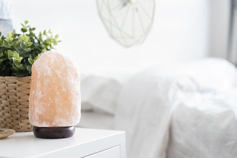 A Himalayan Salt Lamp placed on a night stand of a bedroom