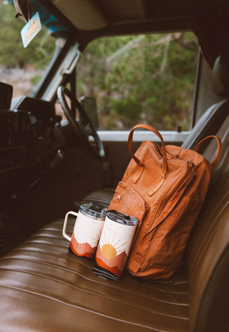 two toddy mugs sitting against a backpack.