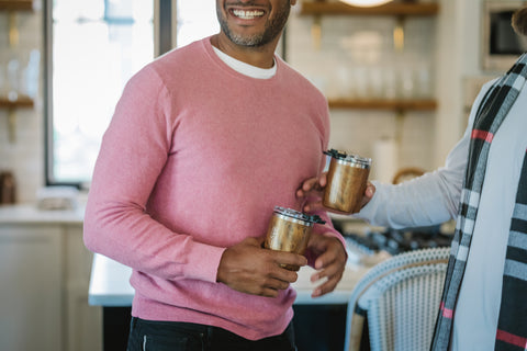 man holding tumbler mug while laughing.