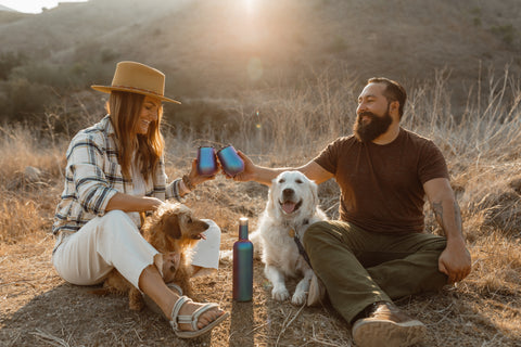 couple and dog sitting on ground. 