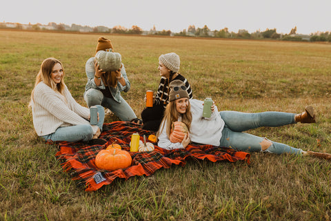 people sitting on ground with pumpkins.