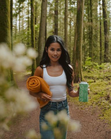 woman walking through the woods with tumbler.