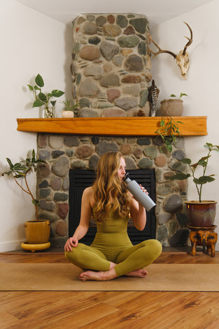 woman in yoga pose with tumbler. 