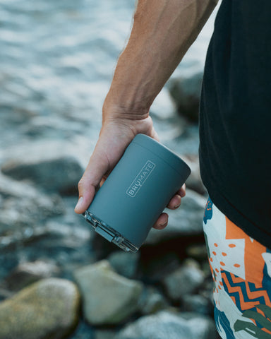 person holding tumbler near river.