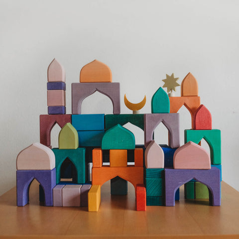 Colorful wooden waldorf Grimm's blocks built to look like a castle with a moon and star seasonal ring decoration 