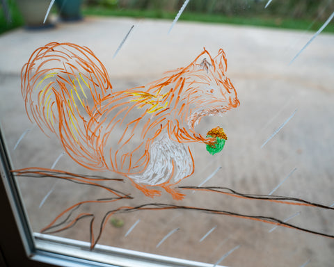 A squirrel drawn on a window with Kitpas window crayons for Halloween decoration.