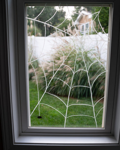 A spiderweb drawn on the window with Kitpas window crayons for Halloween decoration.