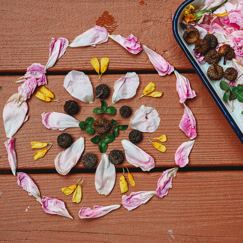 A mandala created with flower petals, clovers, and acorn tops