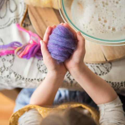Purple wool roving wrapped around an egg to make wet felted Easter eggs.