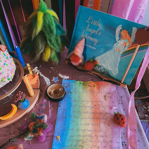 Waldorf birthday table with The Little Angel's Journey book and a rainbow sheet of paper with special birthday wishes written on it