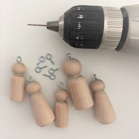 A drill with eyes drilled into the top of the peg dolls to create ornaments