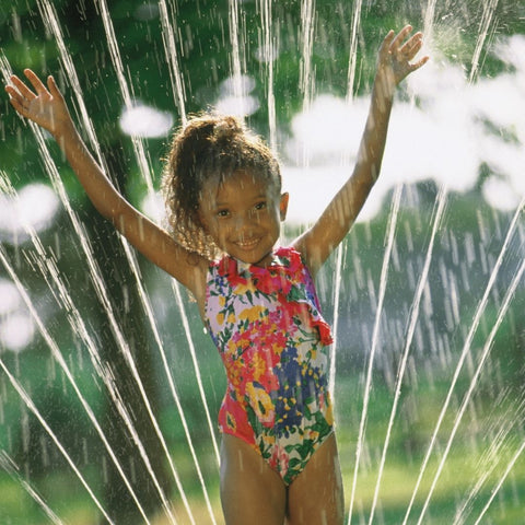 child playing in sprinkler - kid's summer activities calendar 