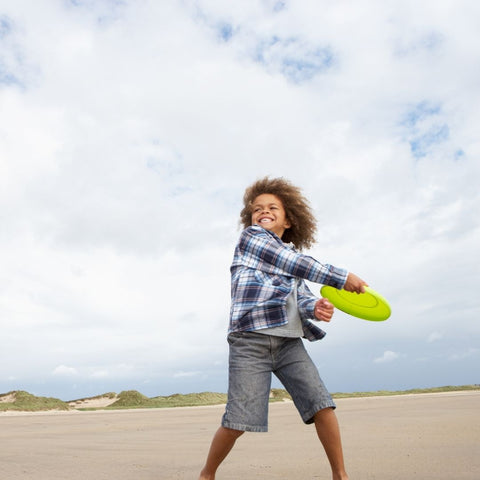 A child tossing a frisbee on the beach outdoor toys