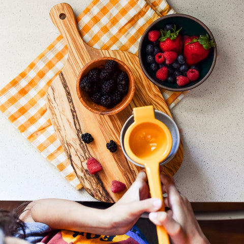 Bowl of berries and hands smashing them into pulp